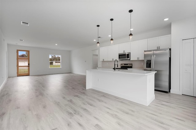 kitchen featuring light wood finished floors, stainless steel appliances, light countertops, visible vents, and white cabinets