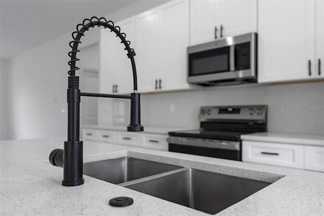 kitchen with light stone countertops, white cabinetry, and appliances with stainless steel finishes