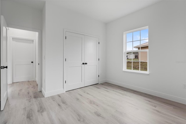 unfurnished bedroom with a closet, baseboards, and wood finished floors