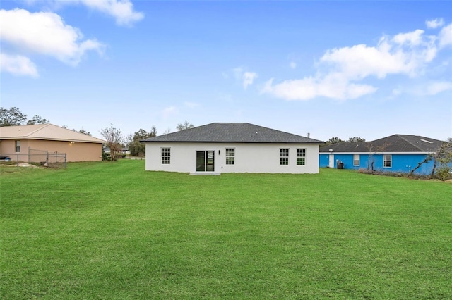 rear view of property featuring fence and a lawn