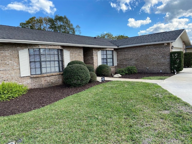 single story home with roof with shingles, a front lawn, and brick siding