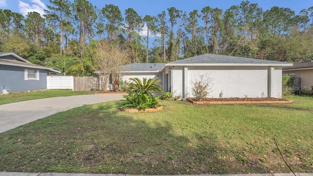 view of front of property featuring stucco siding, fence, concrete driveway, and a front yard