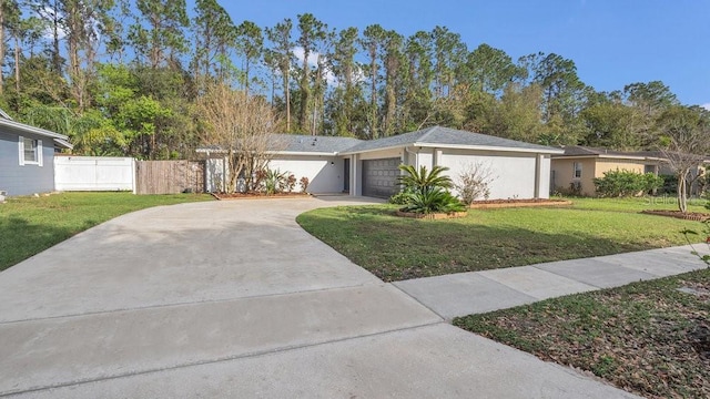 view of front of home with stucco siding, a front yard, fence, a garage, and driveway