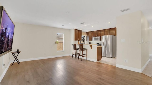 kitchen featuring a breakfast bar area, light countertops, visible vents, appliances with stainless steel finishes, and light wood-style floors