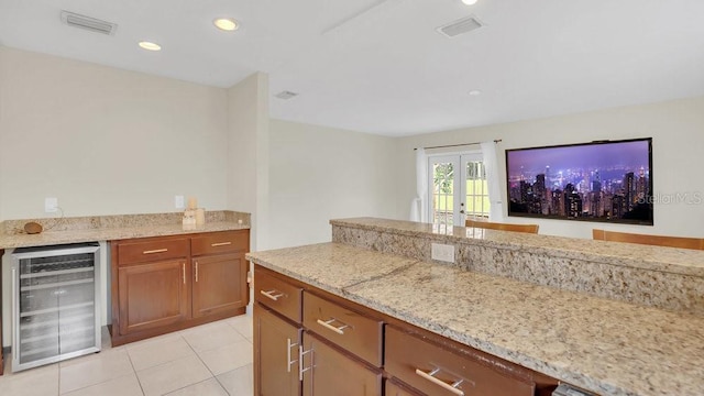 kitchen with beverage cooler, visible vents, and light stone countertops