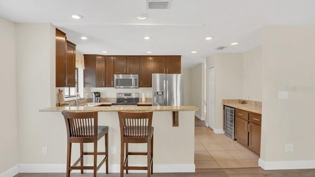 kitchen featuring stainless steel appliances, beverage cooler, visible vents, and a peninsula