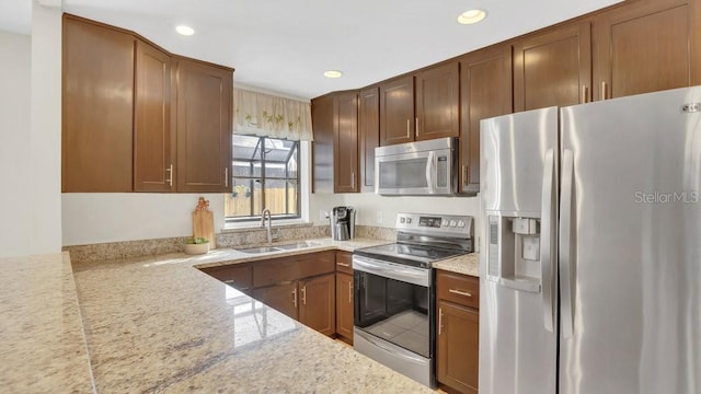 kitchen featuring light stone countertops, appliances with stainless steel finishes, a sink, and recessed lighting