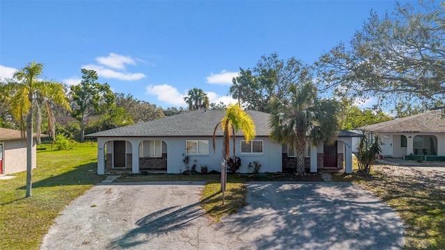 single story home featuring a porch, aphalt driveway, and a front yard