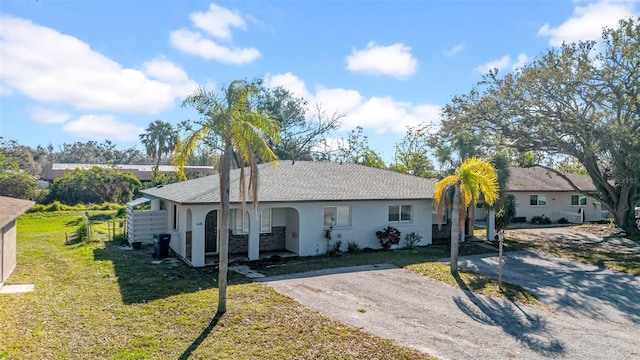 ranch-style house with a front yard, driveway, and stucco siding