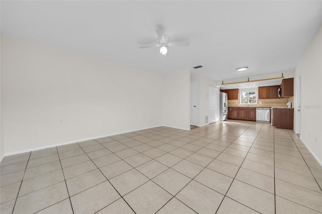 unfurnished living room with light tile patterned floors, visible vents, a ceiling fan, and baseboards