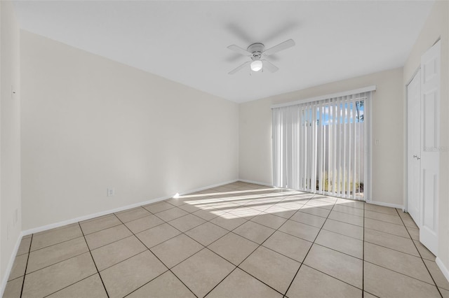 spare room with ceiling fan, baseboards, and light tile patterned floors