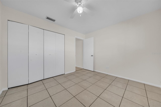 unfurnished bedroom featuring light tile patterned floors, baseboards, visible vents, ceiling fan, and a closet