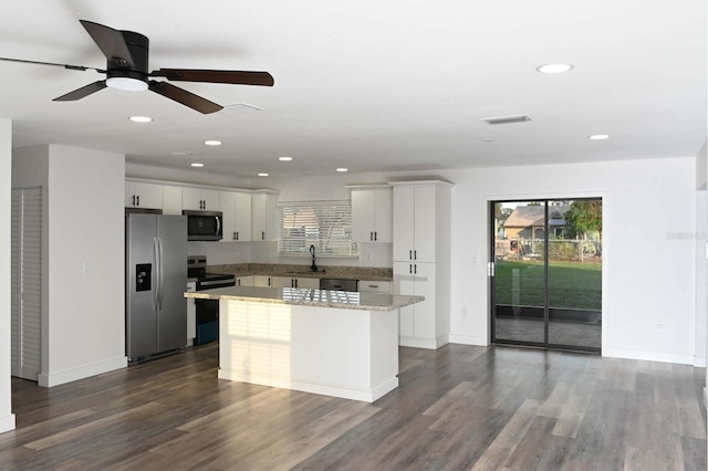 kitchen with a center island, dark wood finished floors, stainless steel appliances, visible vents, and a sink