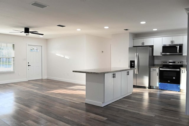 kitchen featuring appliances with stainless steel finishes, dark wood-type flooring, visible vents, and a center island