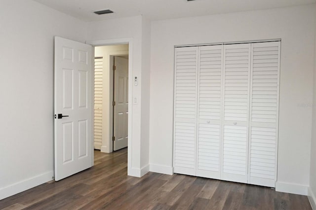 unfurnished bedroom with baseboards, visible vents, and dark wood-style flooring