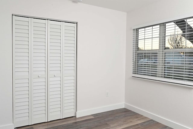 unfurnished bedroom featuring a closet, baseboards, and wood finished floors