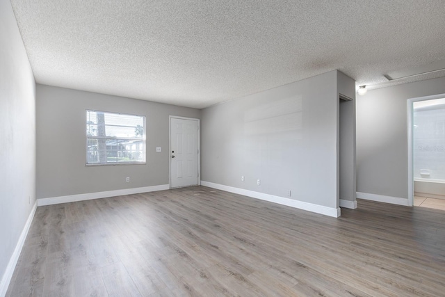 spare room featuring a textured ceiling, baseboards, and wood finished floors