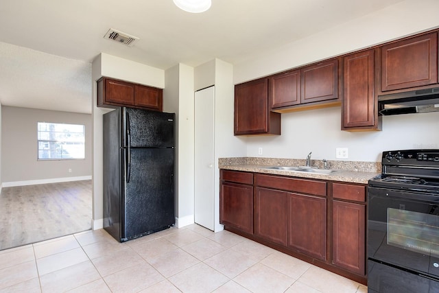 kitchen with under cabinet range hood, a sink, visible vents, light countertops, and black appliances