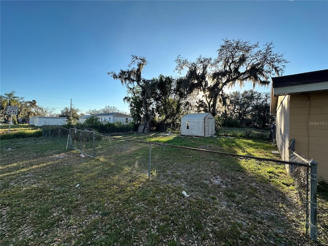 view of yard featuring a shed, fence, and an outbuilding