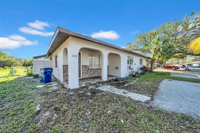 view of front of house featuring stone siding, fence, and stucco siding