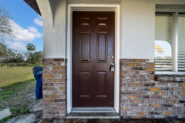 view of exterior entry featuring brick siding and stucco siding