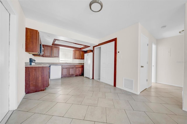 kitchen with light tile patterned floors, white appliances, a sink, visible vents, and light countertops