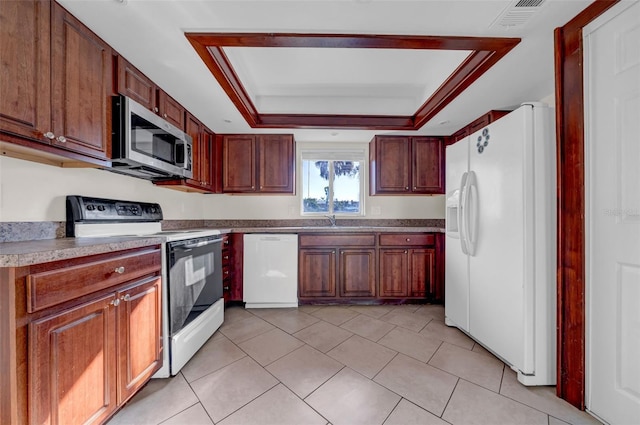 kitchen with white appliances, light tile patterned floors, visible vents, a raised ceiling, and a sink