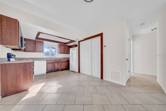 kitchen with white appliances, light tile patterned floors, visible vents, light countertops, and a sink