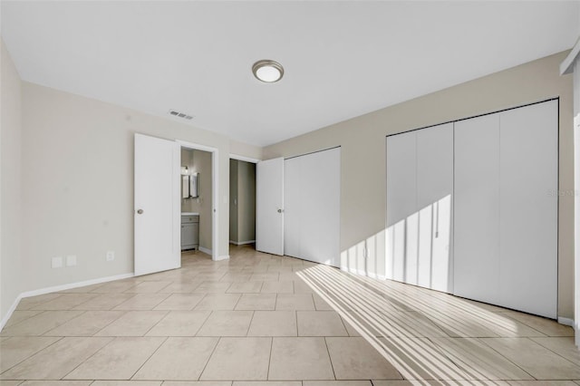 unfurnished bedroom featuring baseboards, visible vents, two closets, and light tile patterned flooring