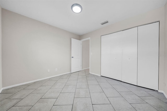 unfurnished bedroom with baseboards, visible vents, a closet, and light tile patterned flooring