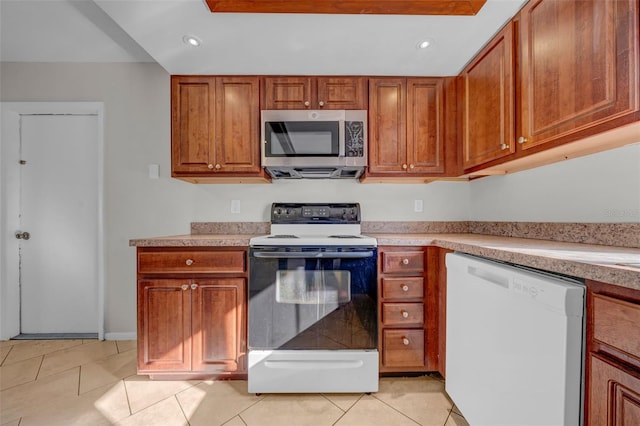 kitchen with brown cabinets, stainless steel microwave, light tile patterned flooring, range with electric cooktop, and dishwasher