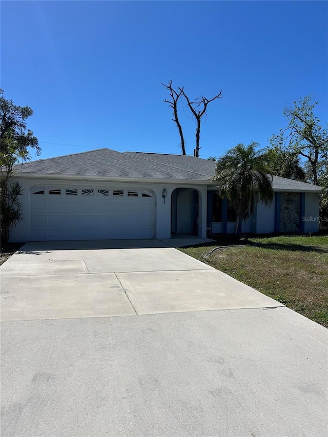 single story home with a garage, concrete driveway, a front yard, and stucco siding