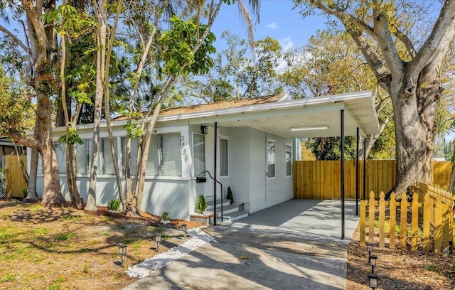 view of front facade with driveway, fence, a carport, and entry steps