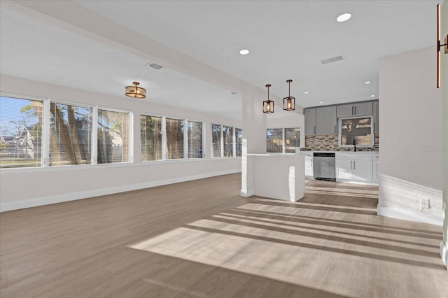 unfurnished living room with light wood-style floors, visible vents, a sink, and recessed lighting