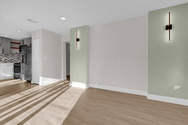 unfurnished living room featuring recessed lighting, light wood-type flooring, visible vents, and baseboards