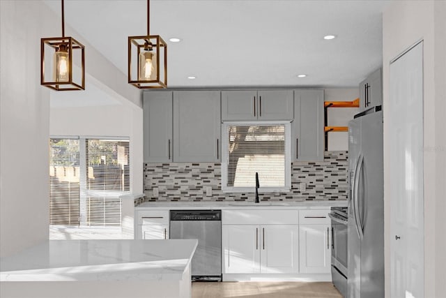 kitchen with stainless steel appliances, gray cabinets, light stone countertops, and decorative backsplash