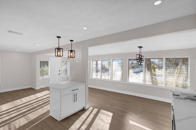 kitchen featuring open floor plan, wood finished floors, visible vents, and decorative light fixtures