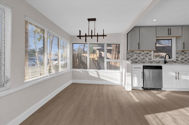 kitchen with tasteful backsplash, dishwasher, gray cabinets, light countertops, and light wood-type flooring