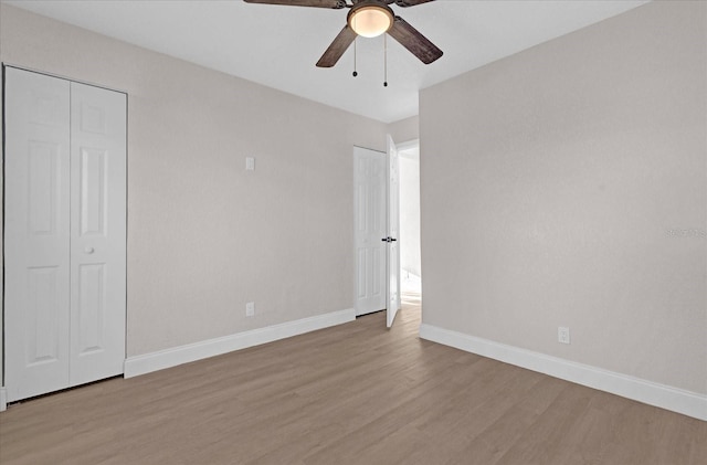 unfurnished bedroom featuring a closet, ceiling fan, baseboards, and wood finished floors