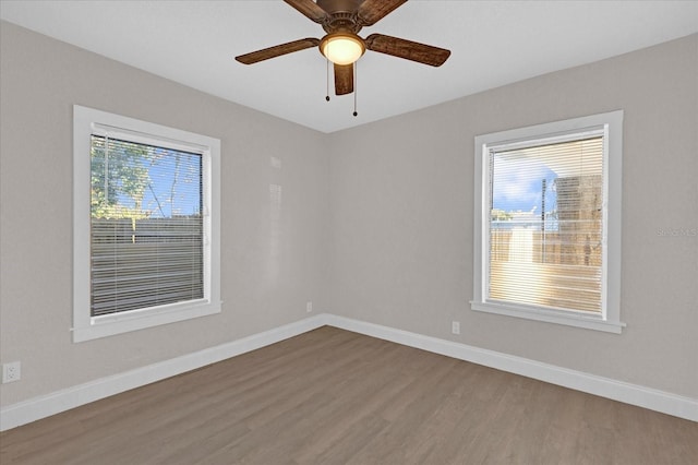 spare room featuring wood finished floors, a ceiling fan, and baseboards