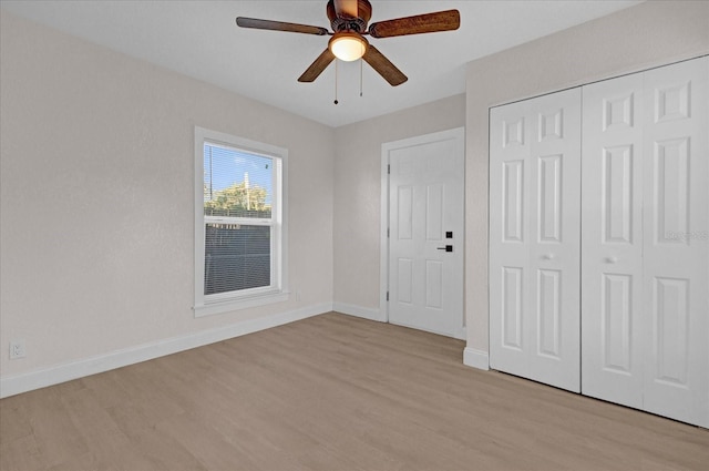 unfurnished bedroom featuring light wood finished floors, ceiling fan, baseboards, and a closet