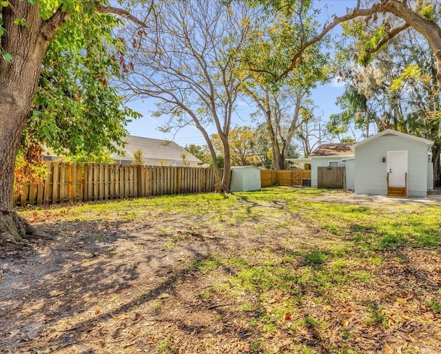 view of yard with a fenced backyard, a storage unit, and an outdoor structure