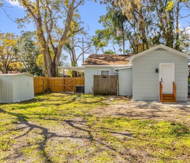 view of yard with entry steps, fence, an outbuilding, and a shed