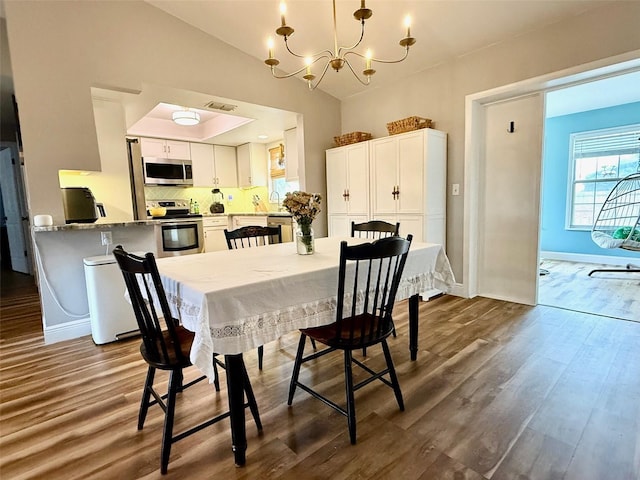 dining space featuring baseboards, visible vents, lofted ceiling, dark wood-style flooring, and a chandelier