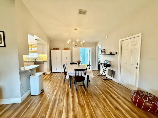 dining area featuring vaulted ceiling, light wood finished floors, visible vents, and an inviting chandelier