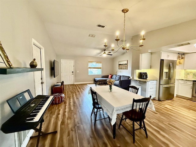 dining area featuring lofted ceiling, light wood-style floors, visible vents, and a chandelier