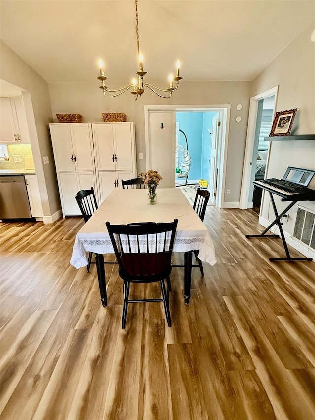 dining room with baseboards, a notable chandelier, and light wood finished floors