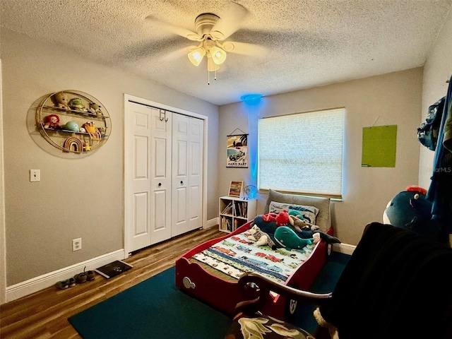 bedroom featuring a closet, ceiling fan, a textured ceiling, wood finished floors, and baseboards