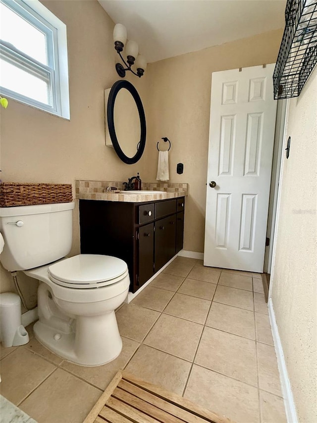 bathroom with baseboards, vanity, toilet, and tile patterned floors