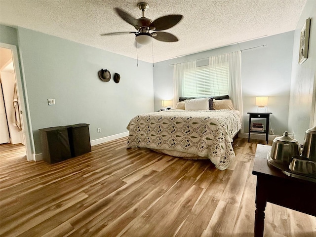 bedroom with a textured ceiling, ceiling fan, wood finished floors, and baseboards